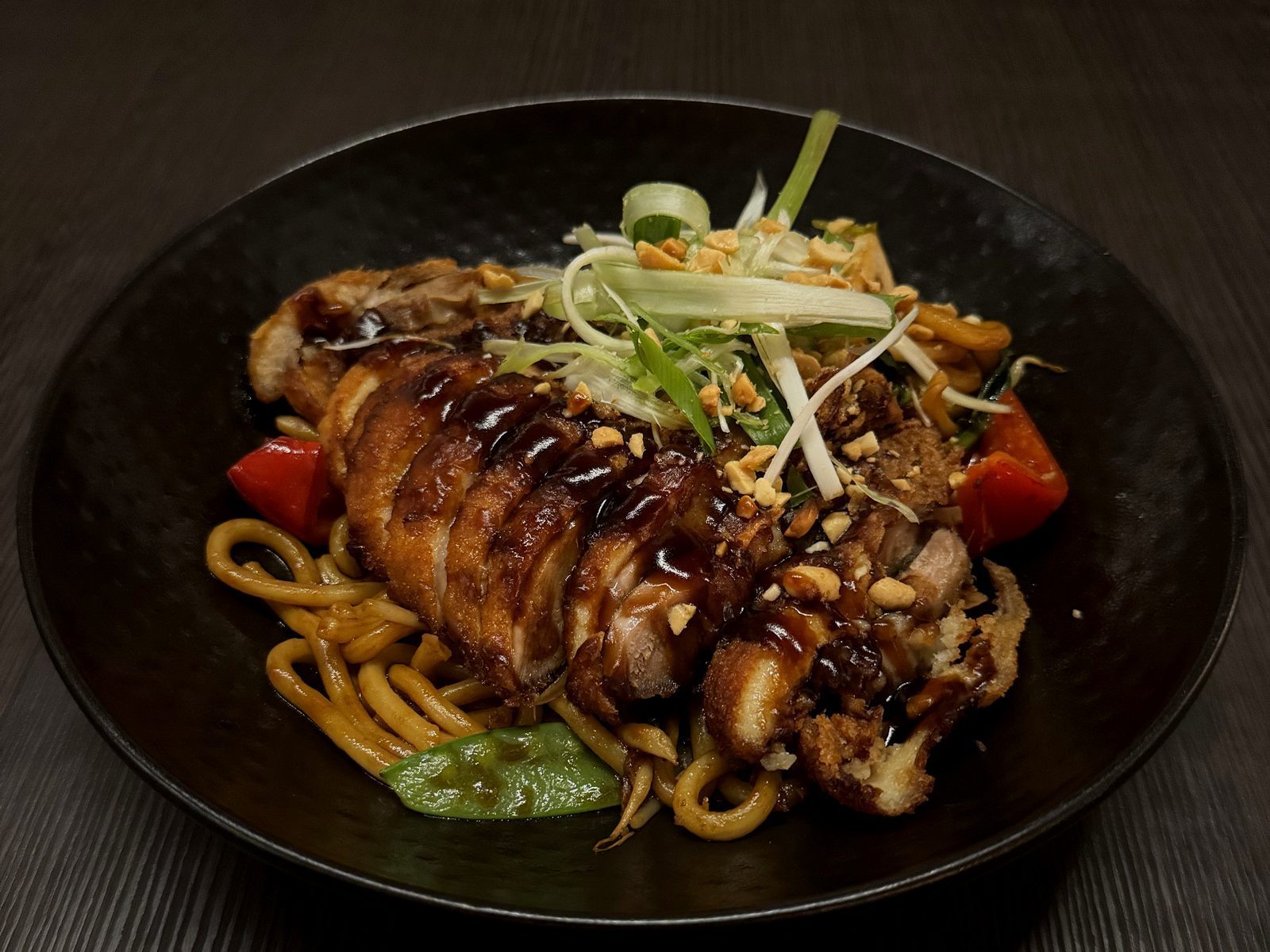 Dunkle Schale mit Udon-Nudeln, glasierter Entenbrust, Erdnüssen und Frühlingszwiebeln