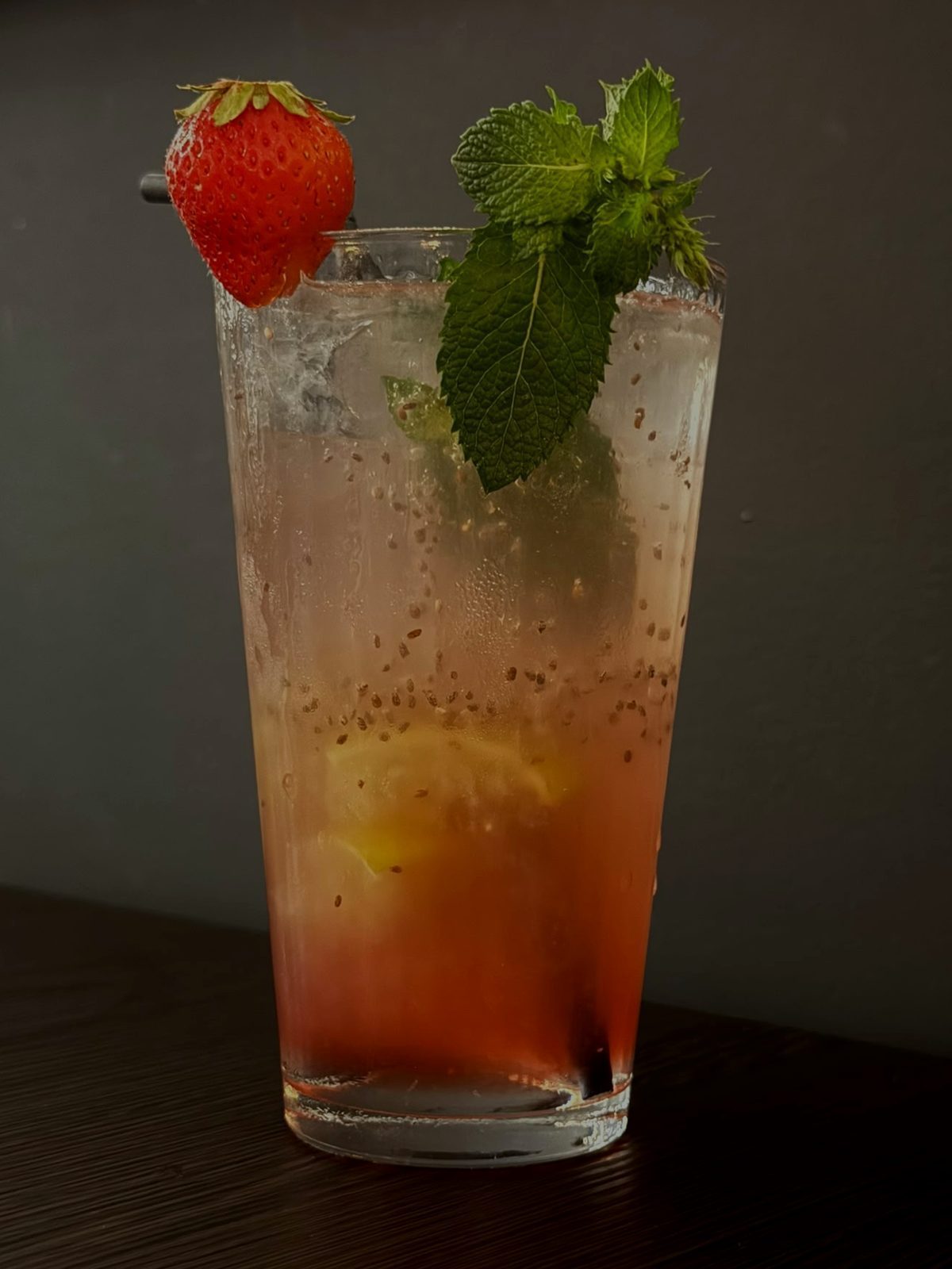 Hohes Glas hausgemachte Limonade mit Erdbeere, frischer Minze und Eis auf dunklem Holztisch